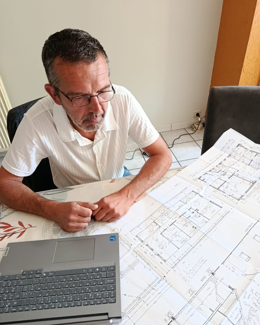 Yves Van Eeckhout au travail sur les plans d'un bâtiment.