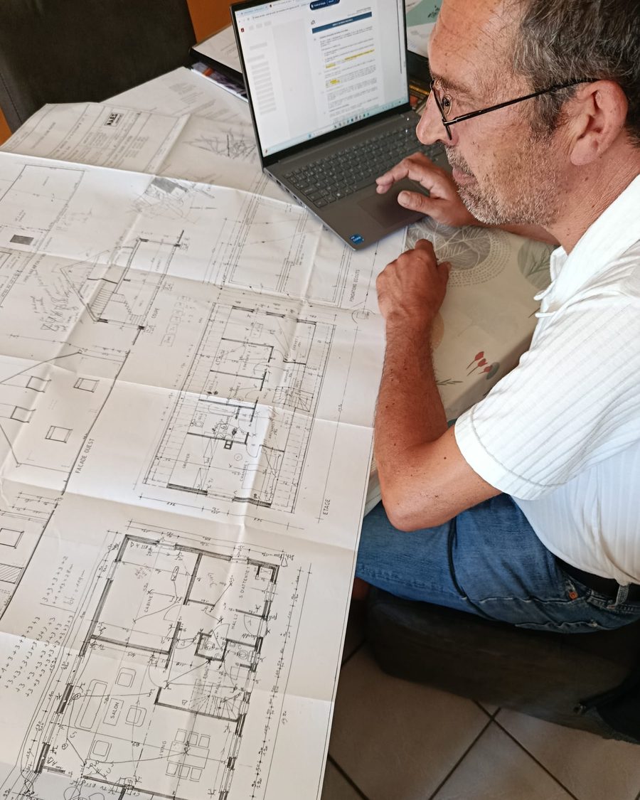 Yves Van Eeckhout analysant les plans d'un bâtiment.